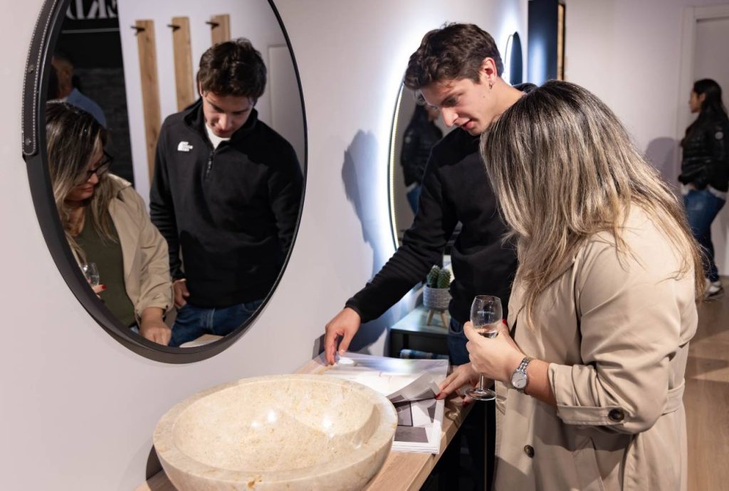Invités observant un lavabo en pierre dans l’espace salle de bains du showroom pendant l’inauguration EKD