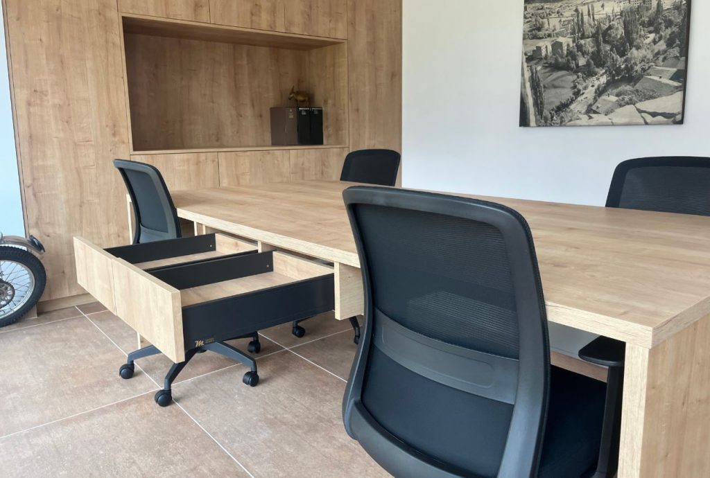 Despatx amb taula de fusta, cadira i paret revestida en un projecte d’interiorisme corporatiu a Andorra